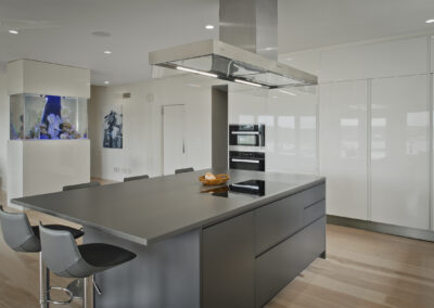 contemporary press and close wall of shiny white cabinetry with gray painted kitchen island